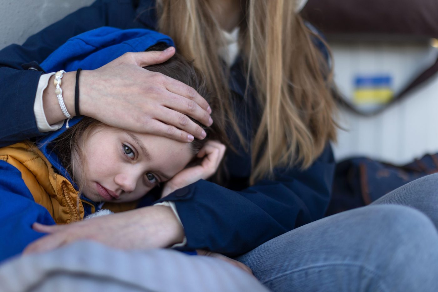 Child embraced by woman, with a comforting hand on her forehead.