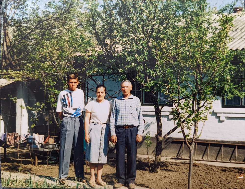 Three people in front of the white house and trees