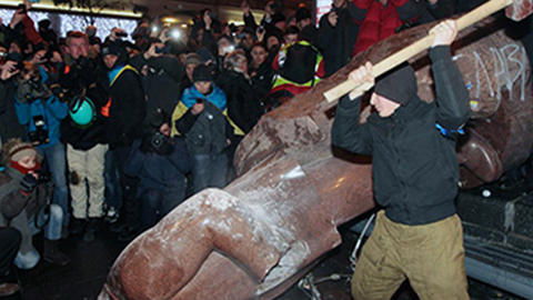 man with sledgehammer with crowd next to fallen statue